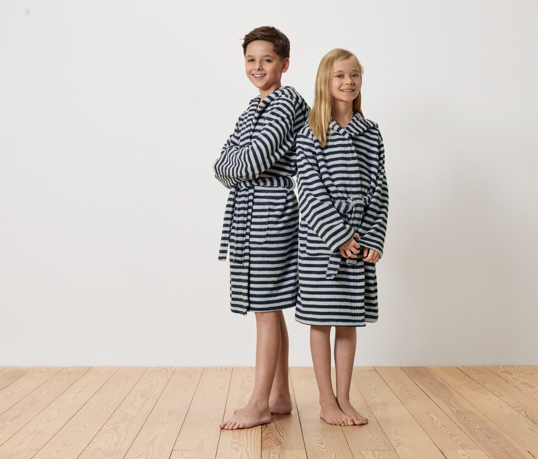 Chlapec a dievča stoja chrbtom k sebe a majú na sebe pruhované župany.