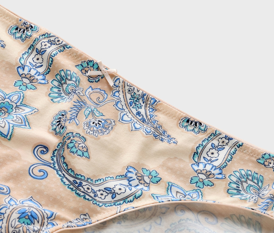 Detailný záber na béžové nohavičky s modrým paisley vzorom a mašľou.