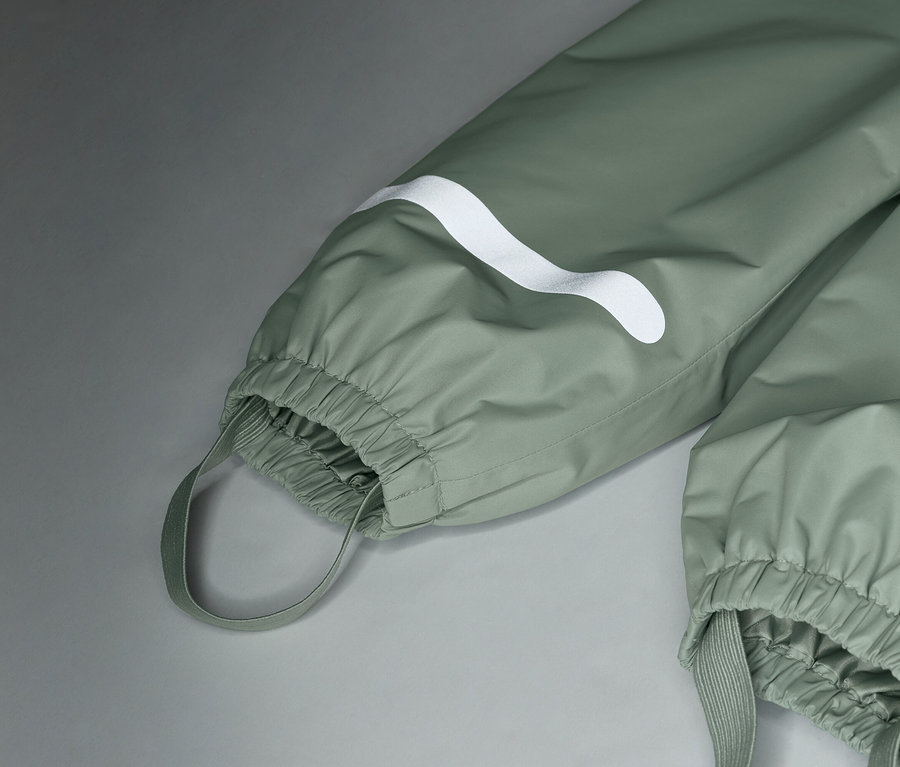 Detailný záber na svetlozelené nepremokavé nohavice s bielym logom a elastickými manžetami.