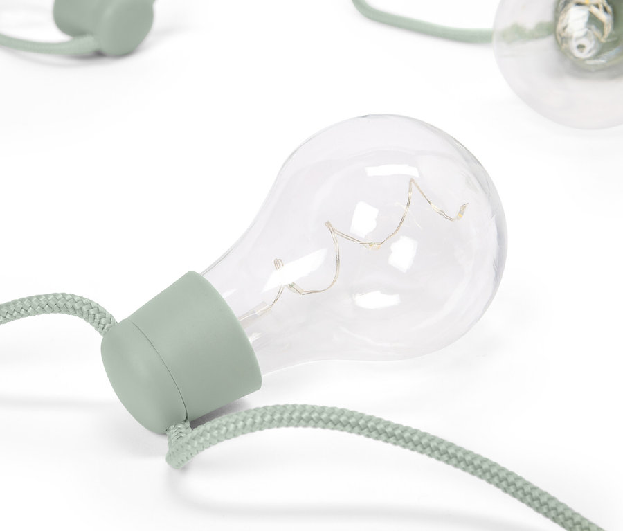 Detailný záber na ozdobné žiarovky so zelenými objímkami a šnúrami na bielom pozadí.