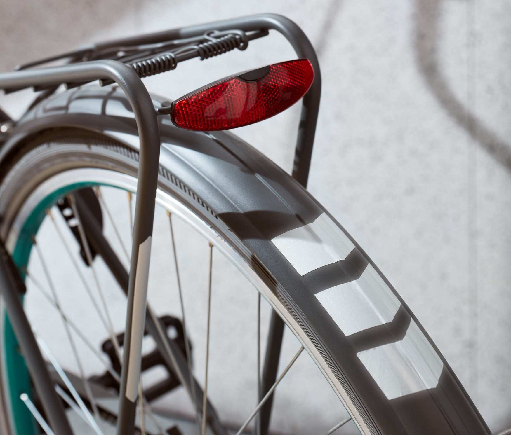 Detail zadného kolesa bicykla s červeným svetlom a reflexnými nálepkami.