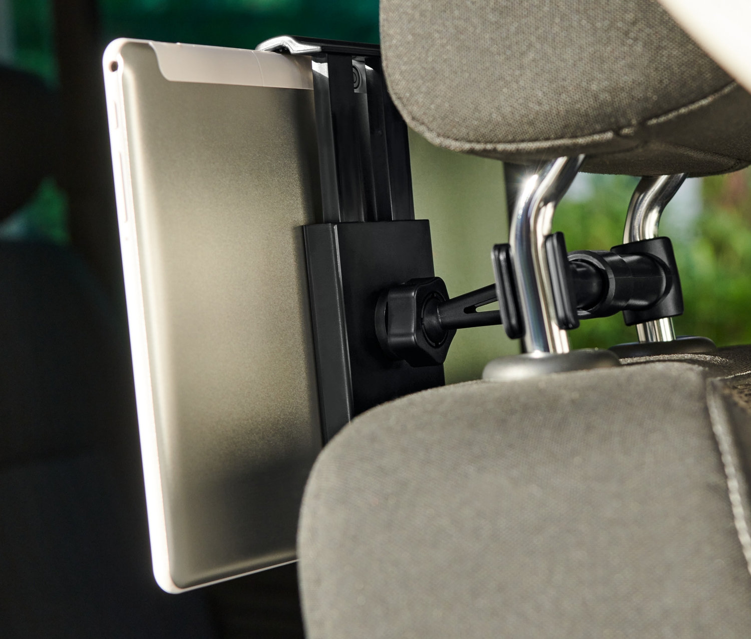 Tablet pripevnený k držiaku tabletu do auta, ktorý je pripevnený k opierke hlavy sedadla.