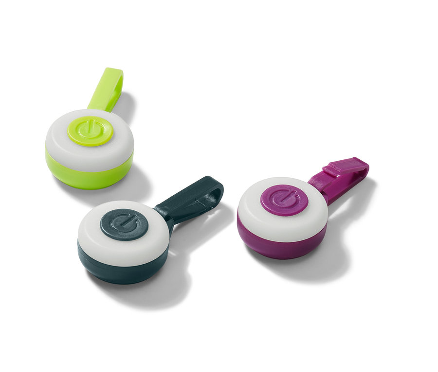 Tri prívesky s LED v zelenej, tmavomodrej a fialovej farbe ležia na bielom povrchu.