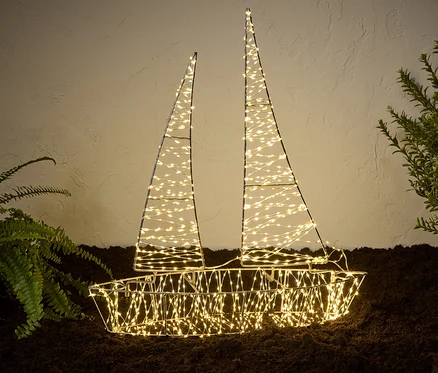 Osvetlená 3D LED vonkajšia loď stojí na zemi vedľa rastlín.