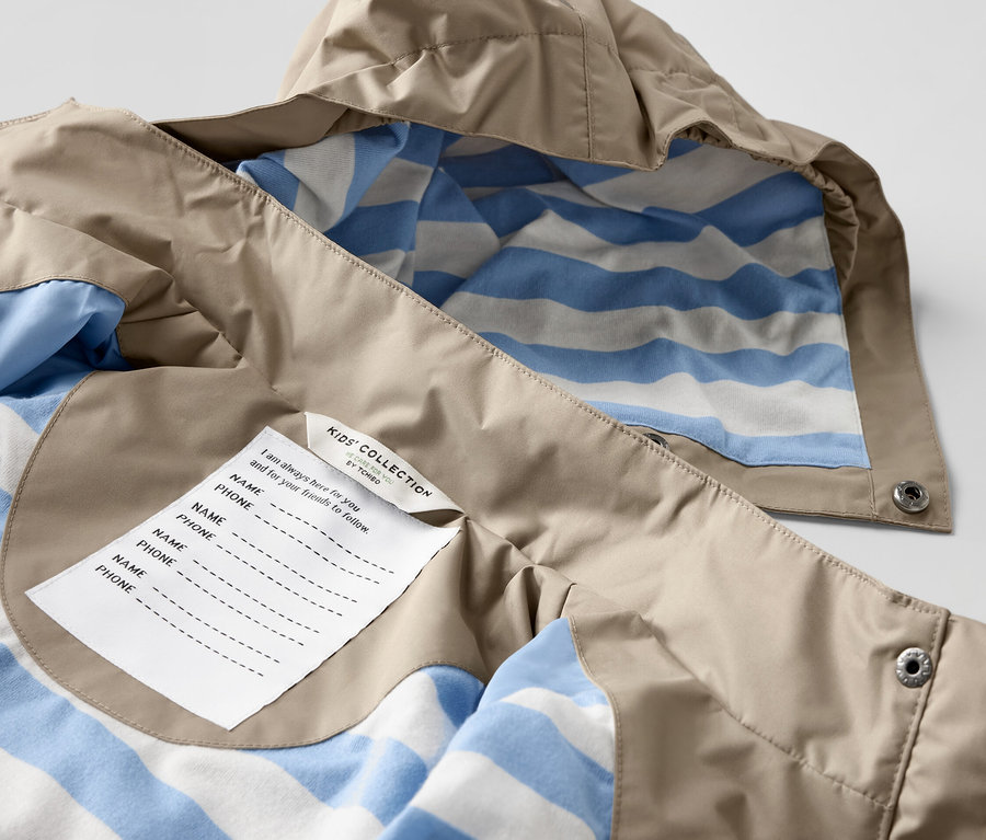 Detail detskej hnedej bundy do dažďa s modro-bielym pruhovaným vnútrom.