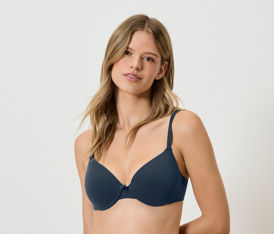 Žena s hnedými vlasmi má na sebe tmavomodrú podprsenku.