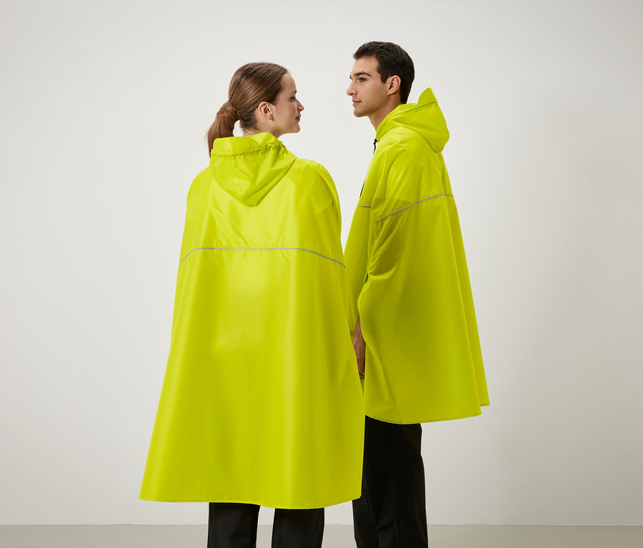 Dvaja ľudia stoja vedľa seba a majú na sebe žlté pršiplášte s kapucňou.