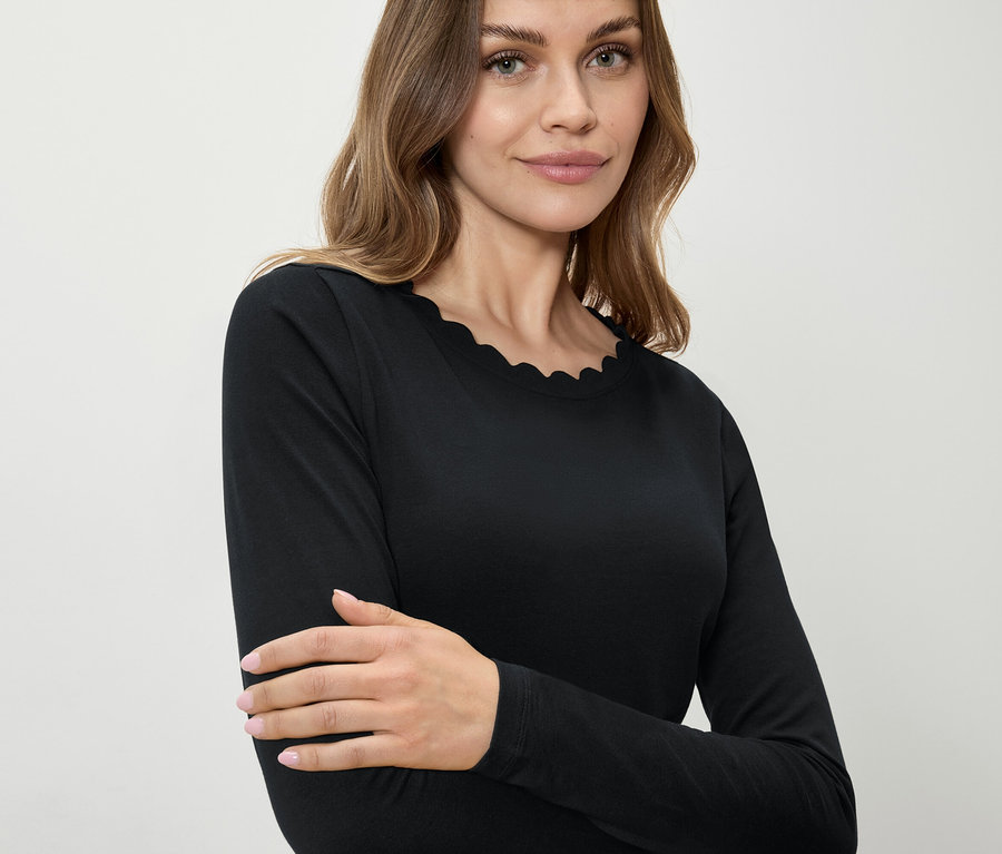 Žena má na sebe čierne tričko s dlhým rukávom a ozdobným lemom.