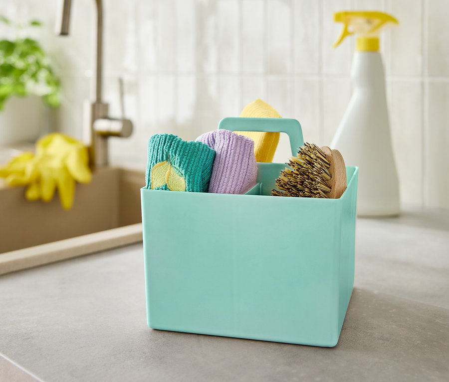 Tyrkysový box s čistiacimi prostriedkami stojí na sivej linke pri dreze.