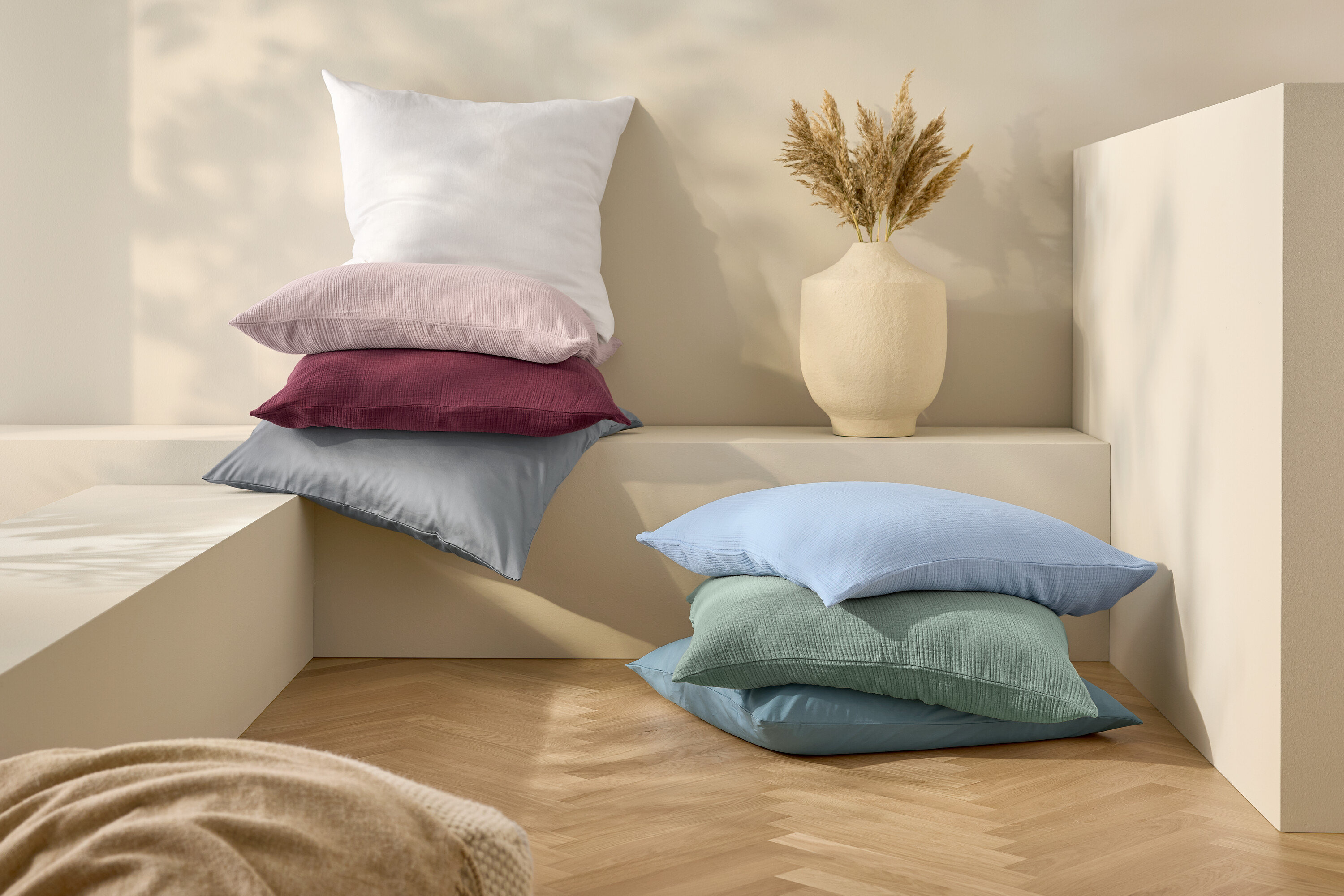 Na sebe naukladané vankúše a ľanové posteľné obliečky bielej štandardnej veľkosti.