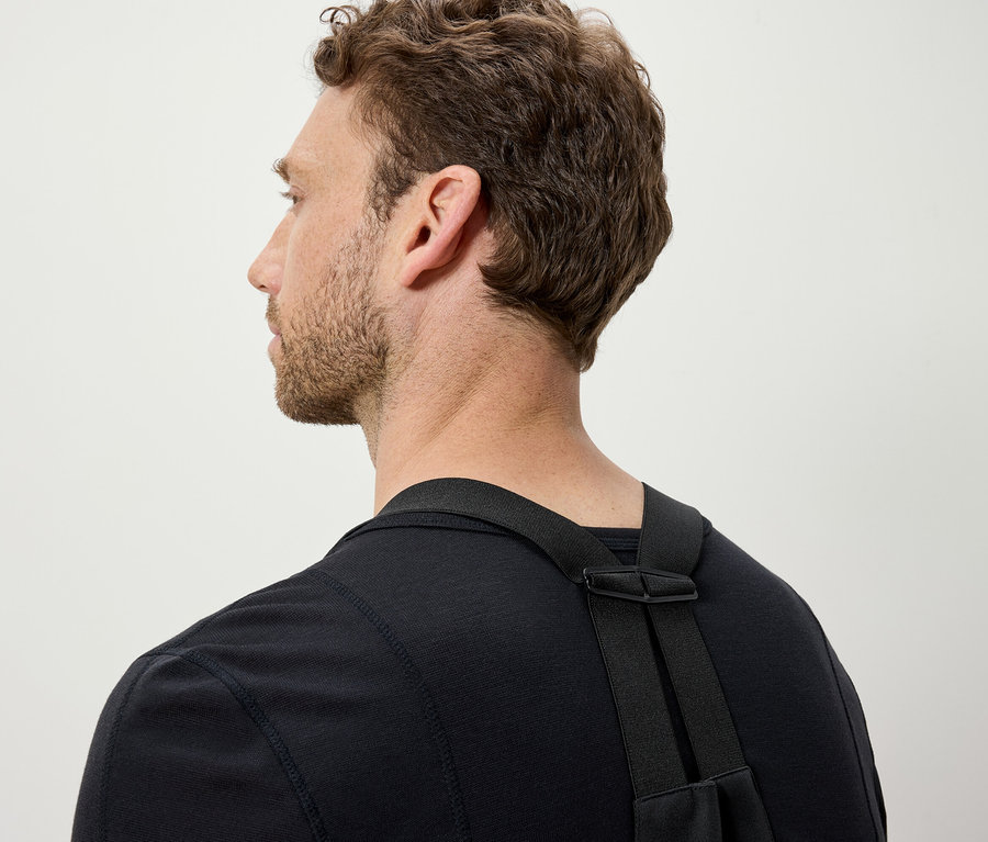 Muž s hnedými vlasmi má na sebe čierne tričko a čierne popruhy.