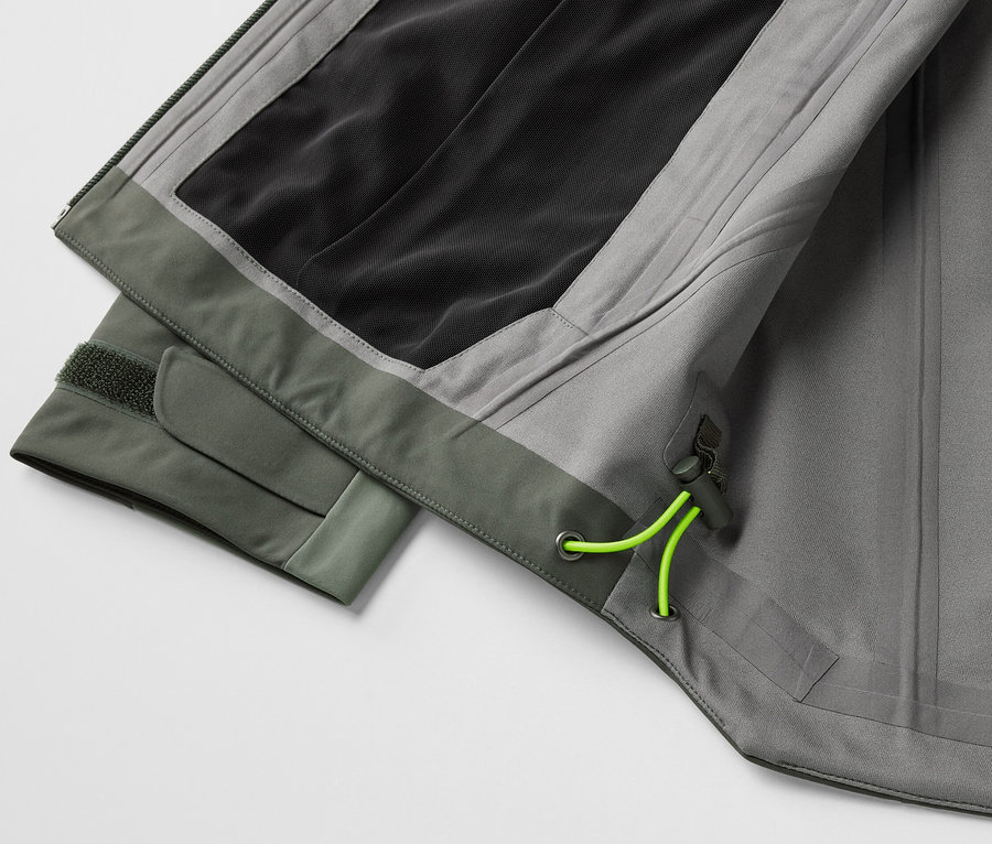 Detail šedej 3-vrstvovej outdoorovej bundy so zelenými prvkami.