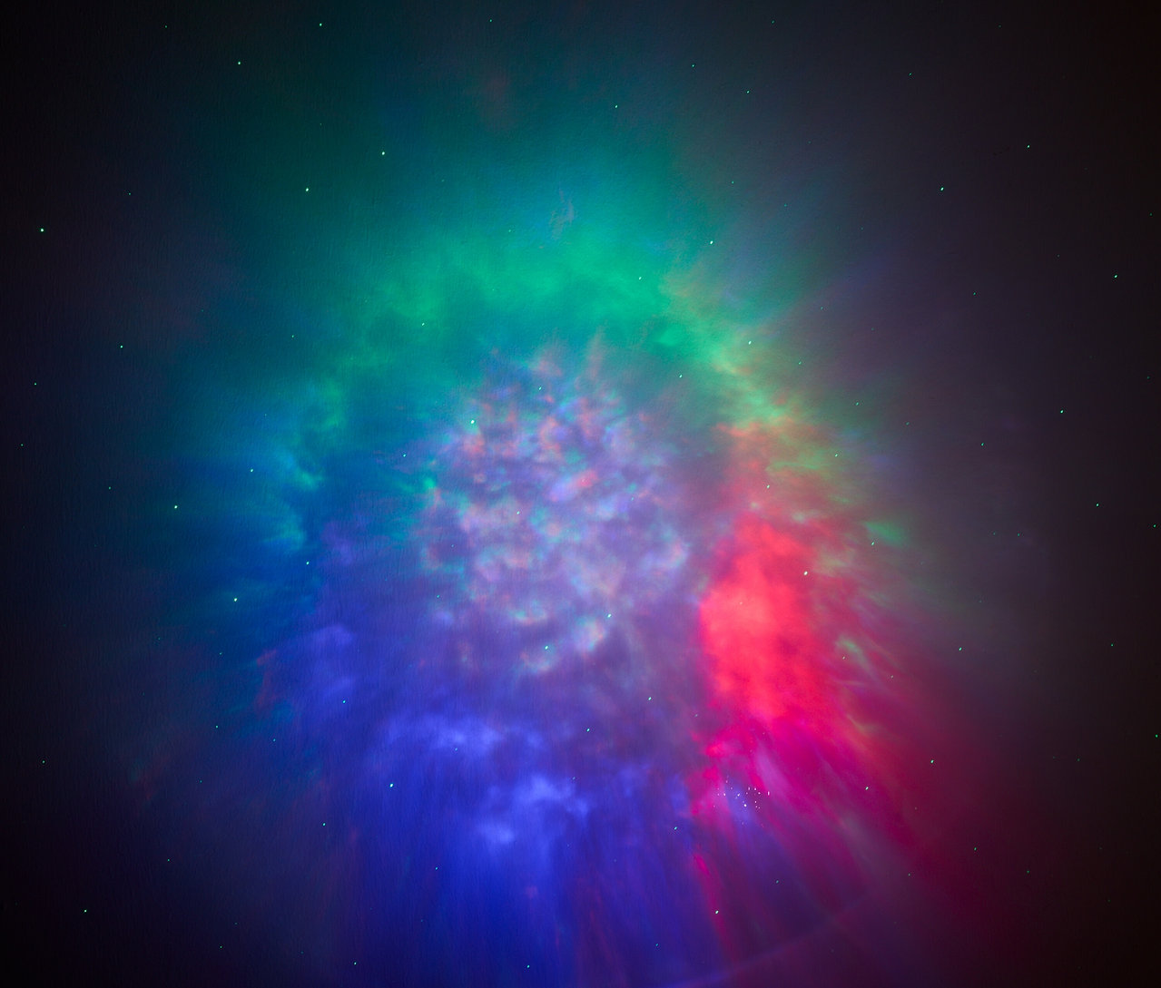 Hmlovina s odtieňmi zelenej, červenej a modrej farby na tmavom pozadí.