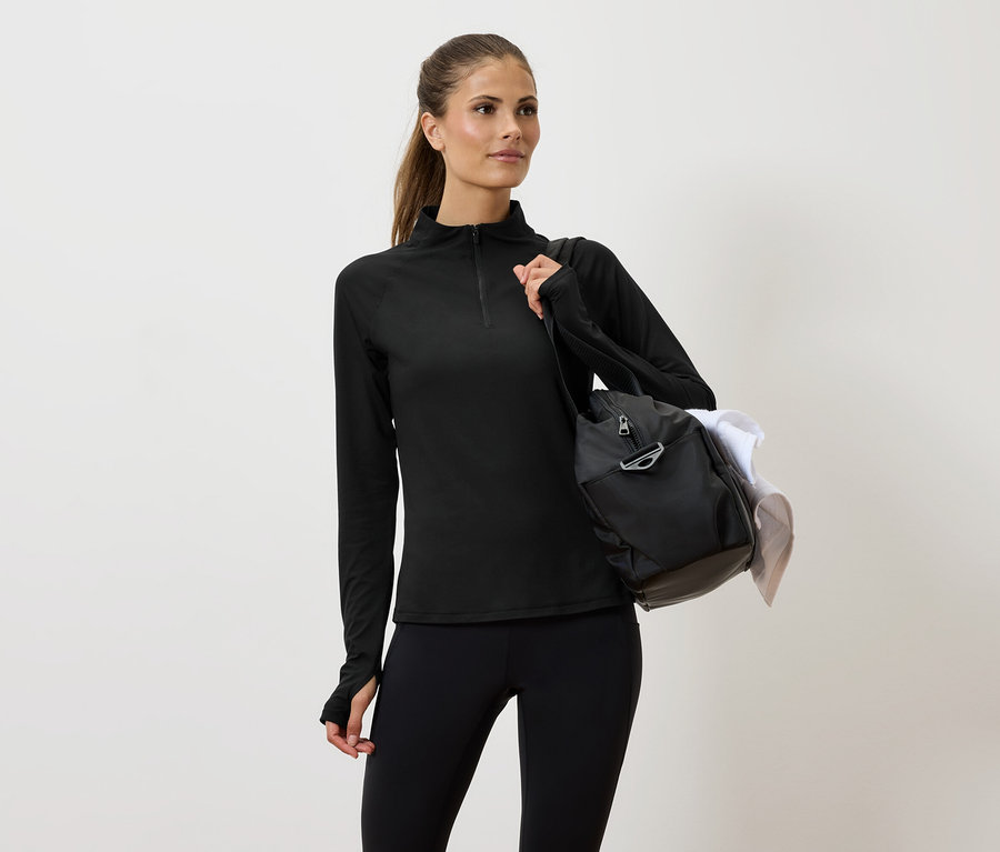Žena v čiernom športovom oblečení s taškou cez rameno.