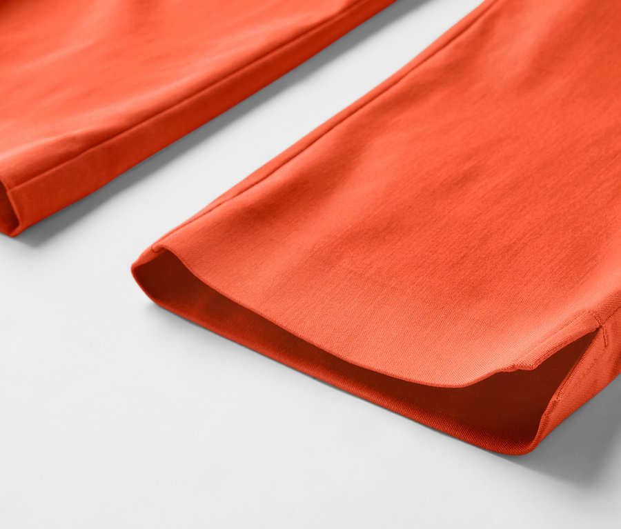 Detail oranžových 3/4 elastických nohavíc.