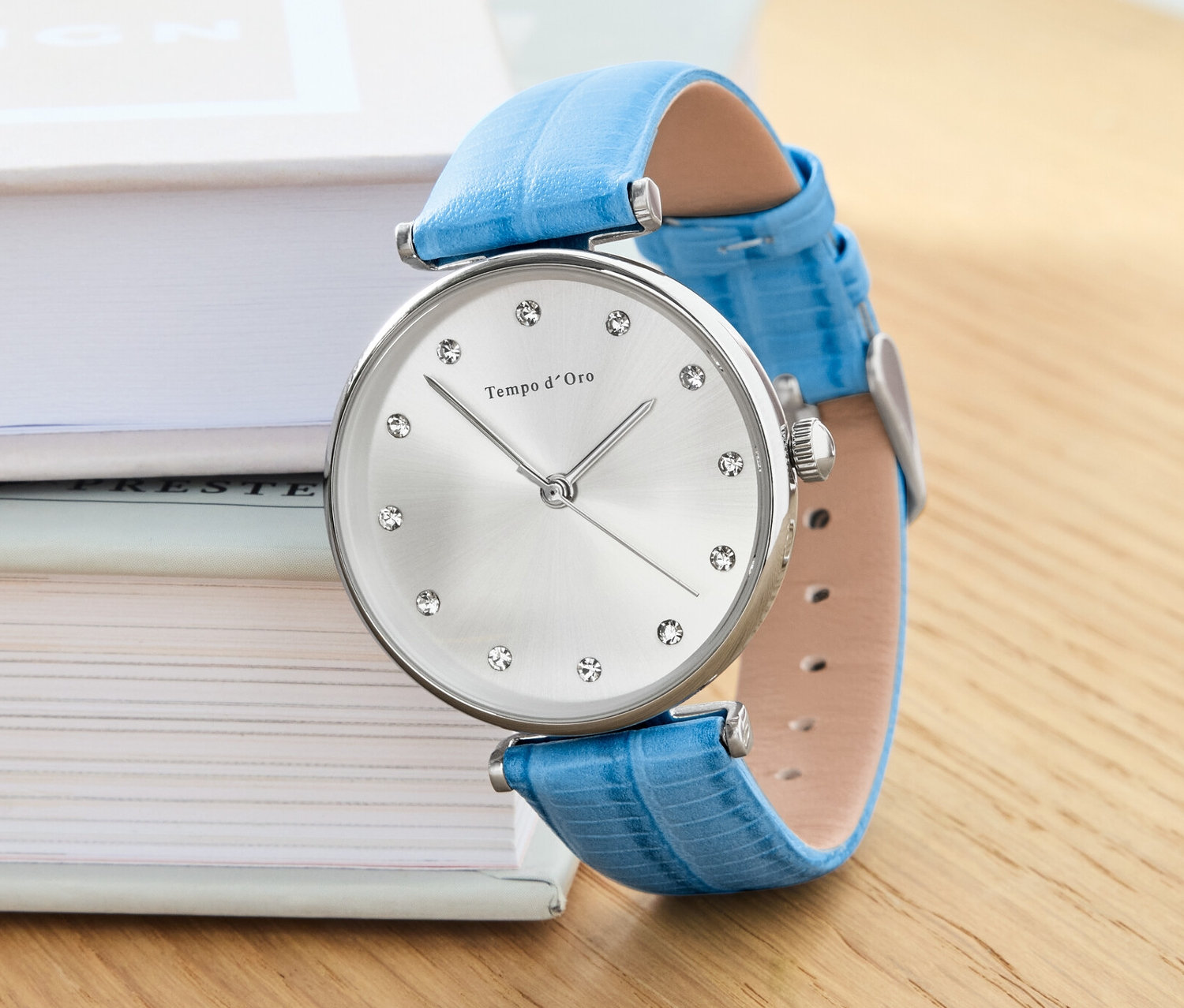 Náramkové hodinky s koženým remienkom a kryštálmi ležia na knihách.