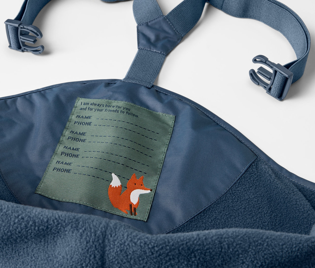 Detail modrých detských termo nohavíc do dažďa s náprsenkou a štítkom s líškou.