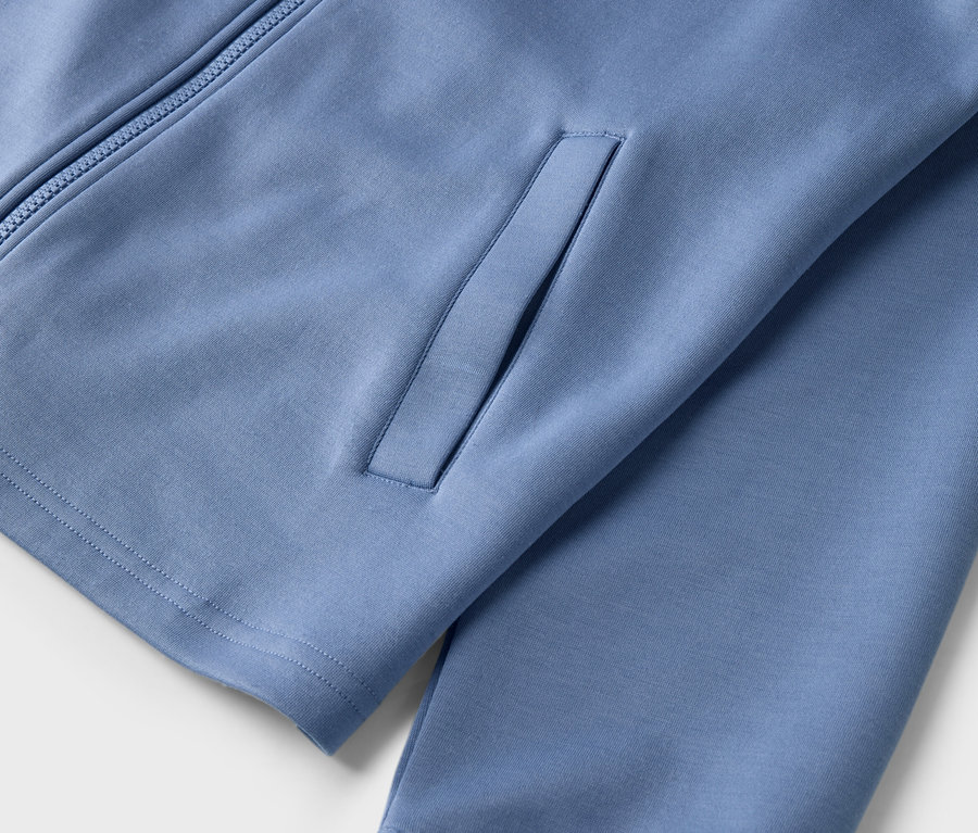 Detail modrej športovej bundy na zips s vreckom.