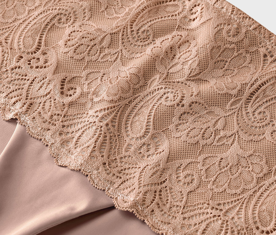 Detail béžovej čipky na béžovej látke.