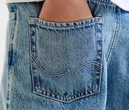 Detail ruky v zadnom vrecku svetlomodrých džínsov s viditeľným prešívaním.