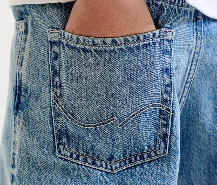 Detail ruky v zadnom vrecku svetlomodrých džínsov s viditeľným prešívaním.