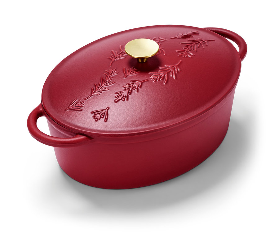 Červený liatinový oválny pekáč s reliéfom ihličia a zlatou rukoväťou.