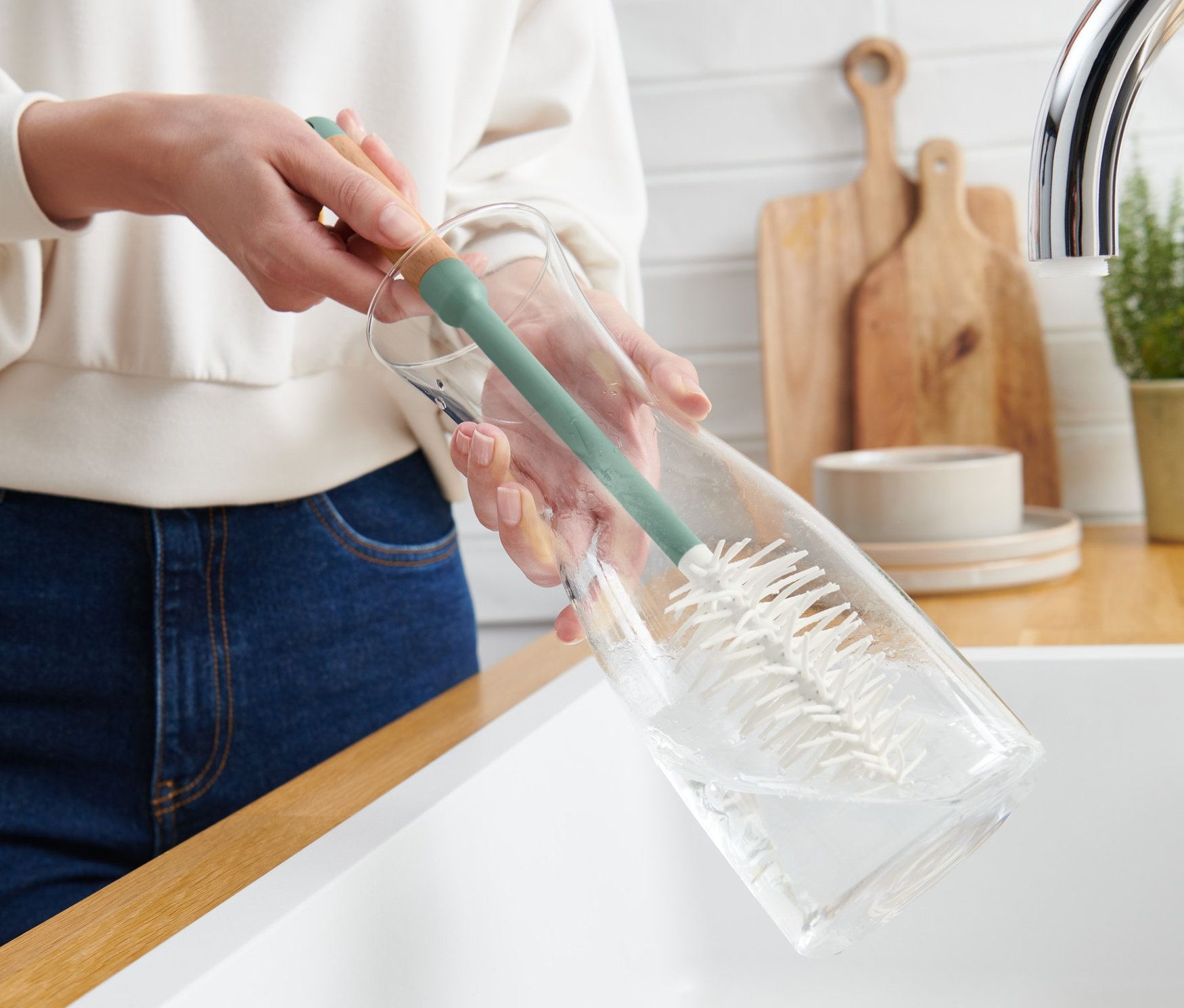 Žena čistí sklenenú fľašu pomocou kefy na čistenie pohárov a fliaš.