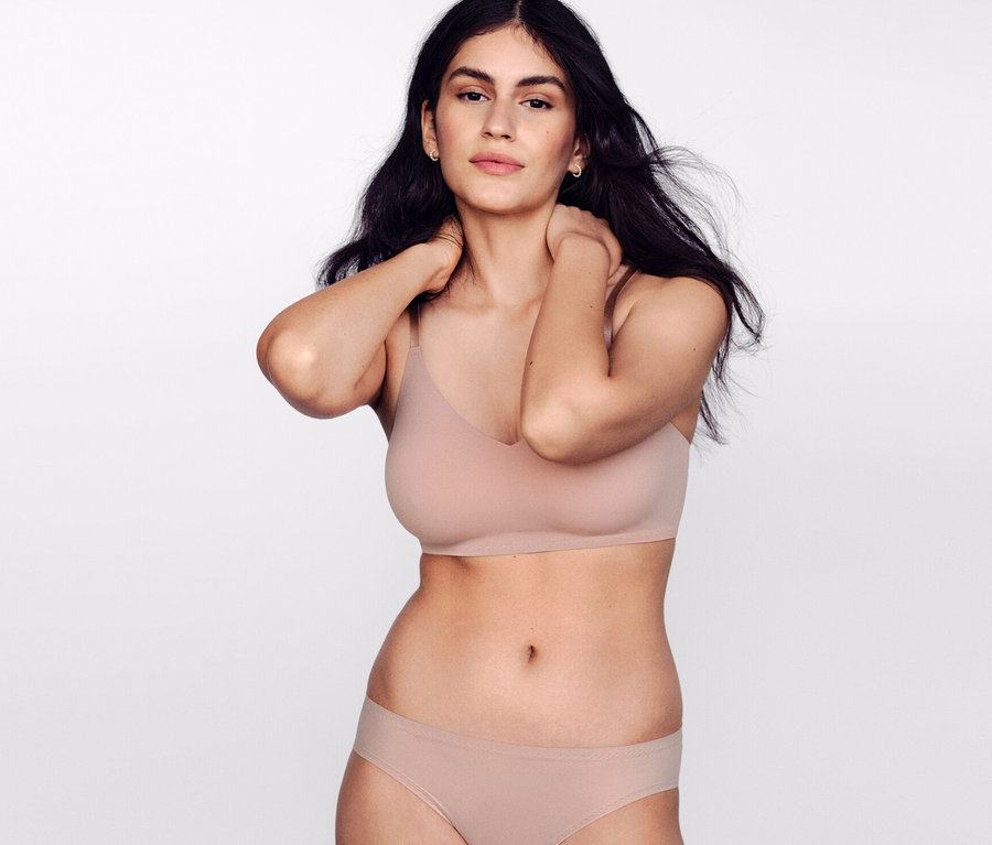 Žena pózuje v SCHIESSER neviditeľnej podprsenke s vložkami, telovej.