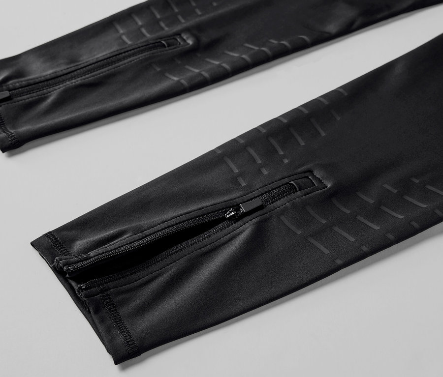 Detailný pohľad na čierne bežecké legínsy so zipsami na nohaviciach.