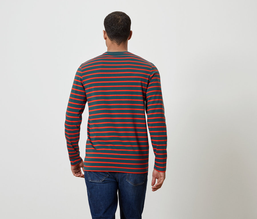 Muž chrbtom k fotoaparátu má na sebe pruhované tričko s dlhým rukávom a džínsy.