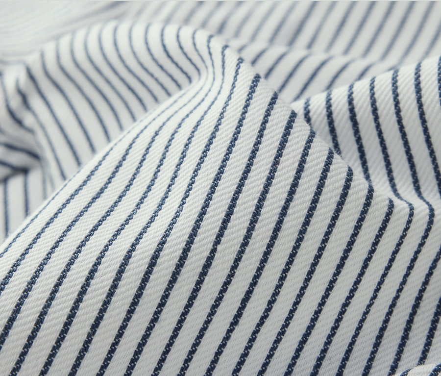 Detailný záber na detské tkané nohavice s modrými prúžkami na bielom pozadí.