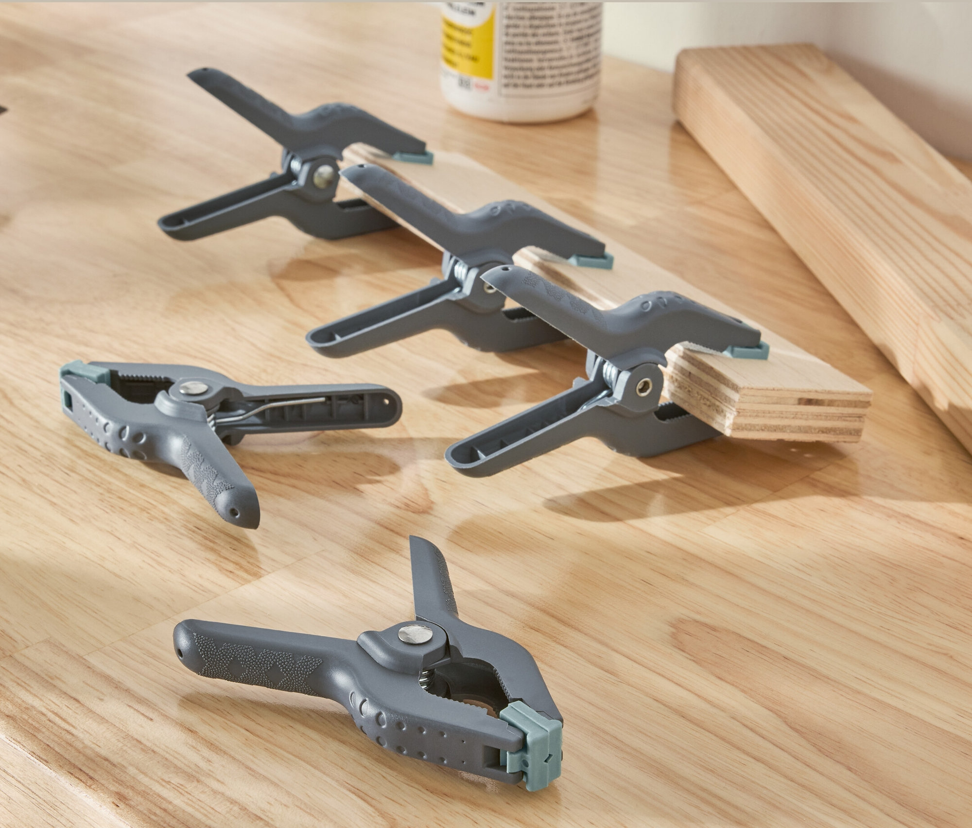 Na drevenom povrchu ležia vŕtačka a päť sivých pružinových svoriek.