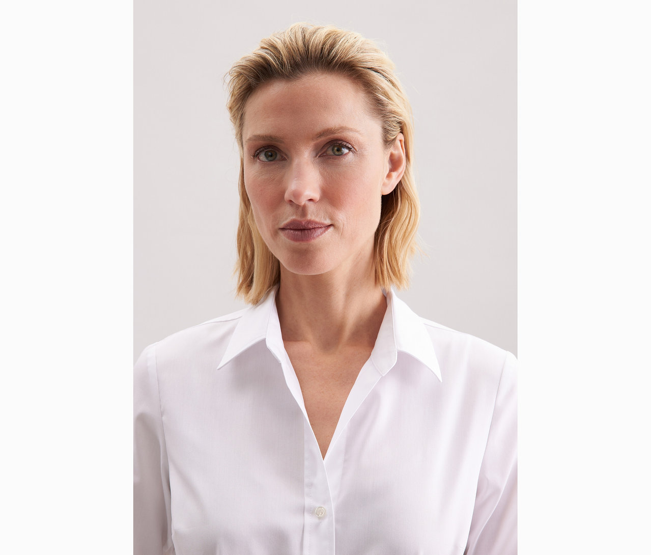 Žena má na sebe bielu blúzku Seidensticker Slim Fit non iron.