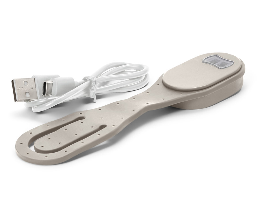 Béžová spona na knihy so svetlom a priloženým nabíjacím USB káblom leží na bielom pozadí.