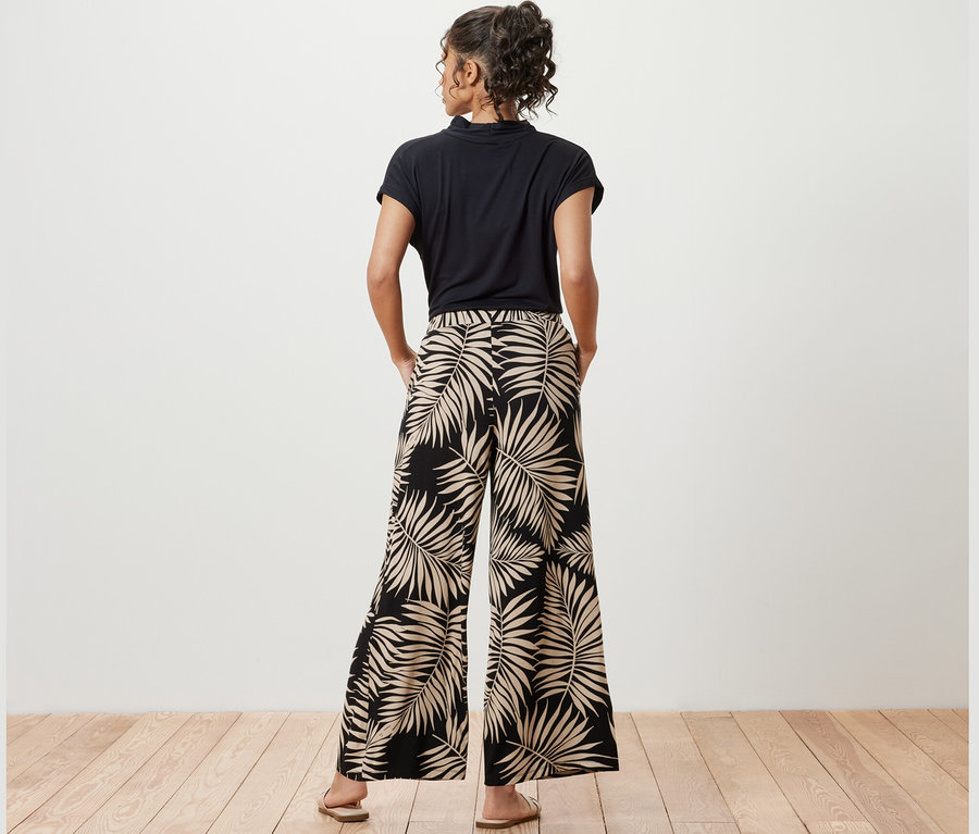 Žena pózuje v nohaviciach v štýle palazzo s potlačou.