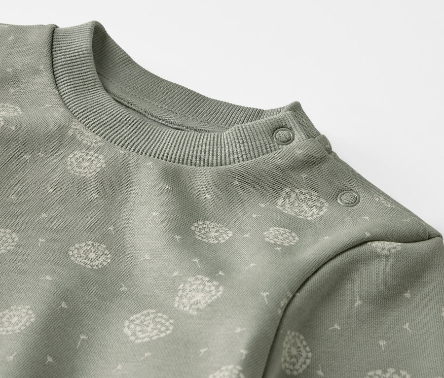 Detail zelenej teplákovej súpravy s potlačou púpav.