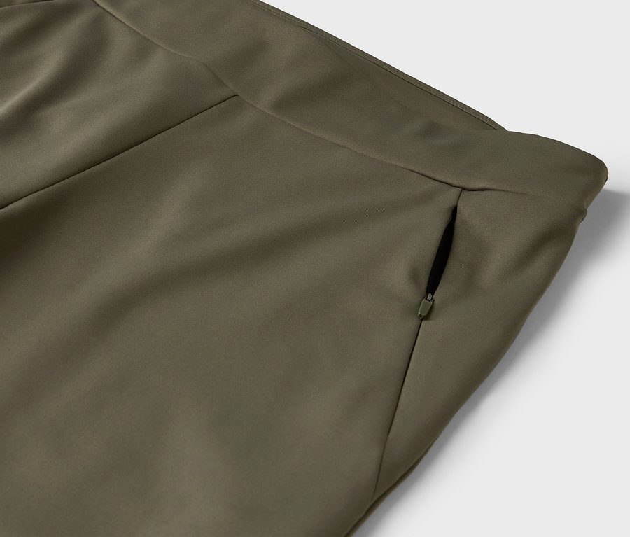 Detail olivovo zelených nohavíc s vreckom na zips.