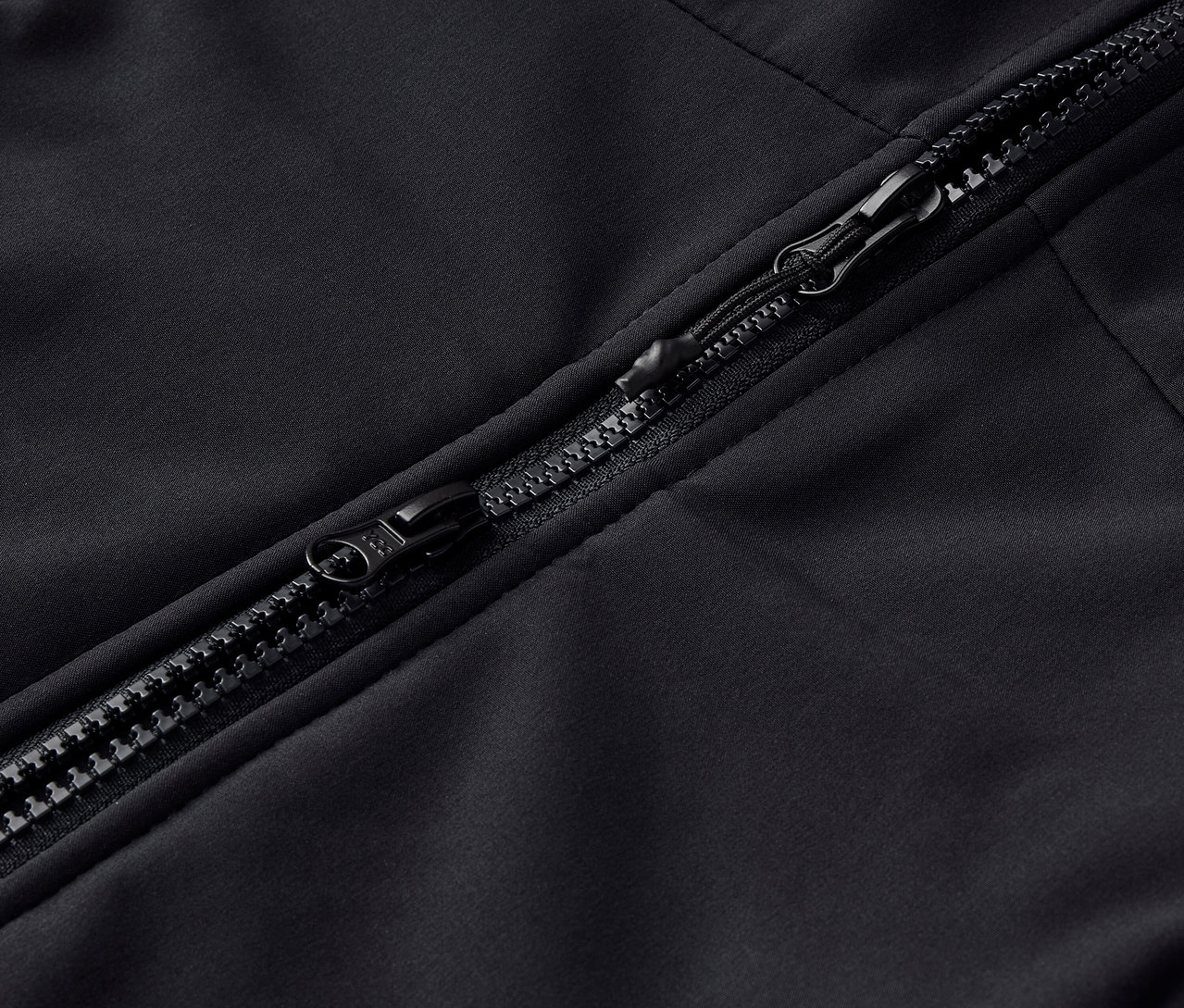 Detail čierneho zipsu na odeve.