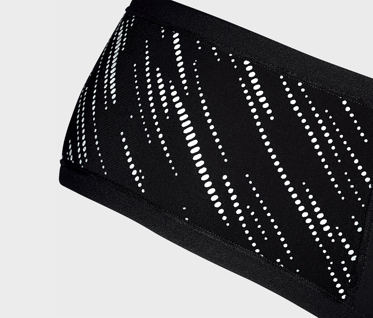 Detailný záber na čiernu čelenku Windprotection-Stirnband s bielym vzorom.