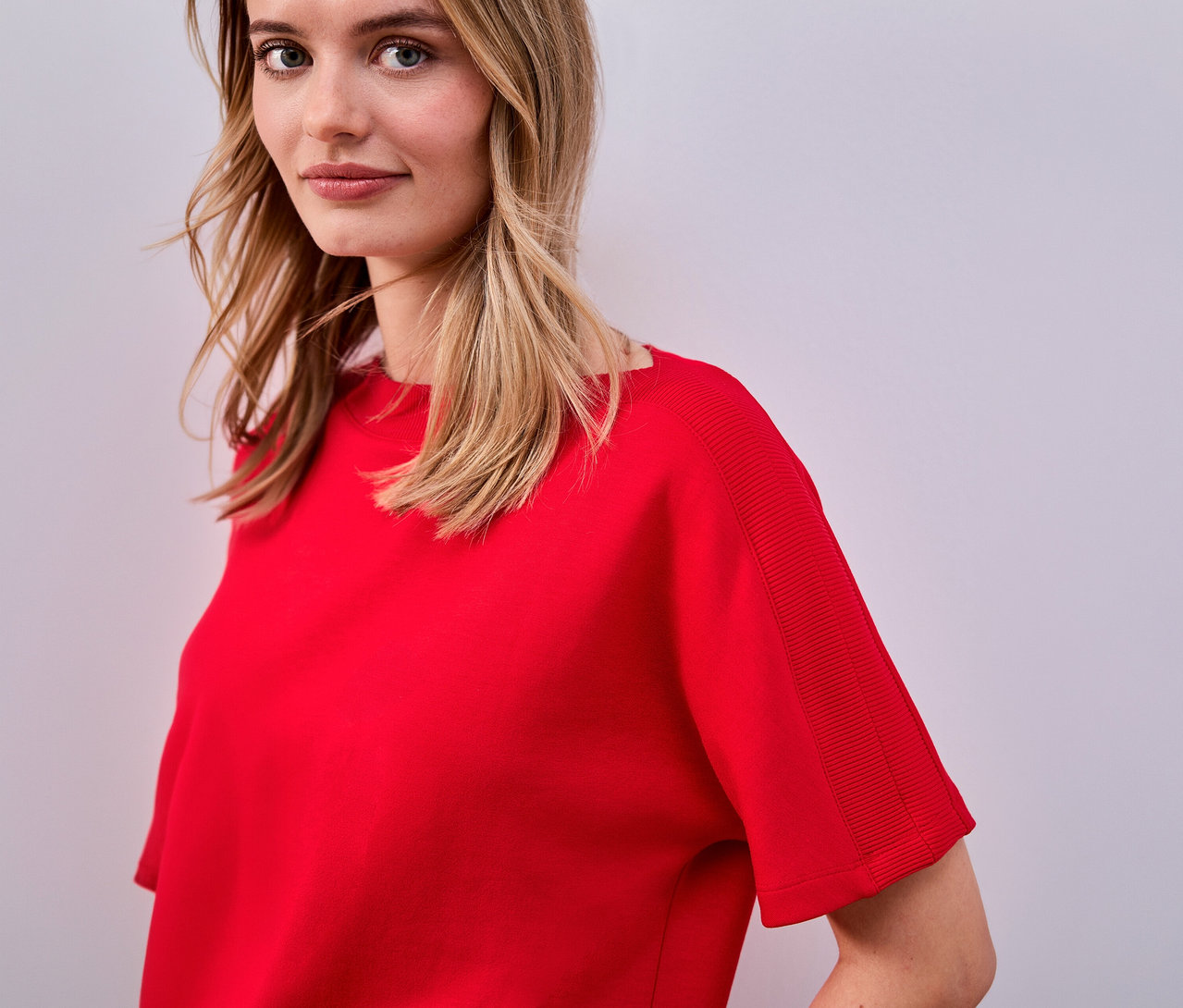 Žena má na sebe červené tričko s krátkym rukávom Street One.