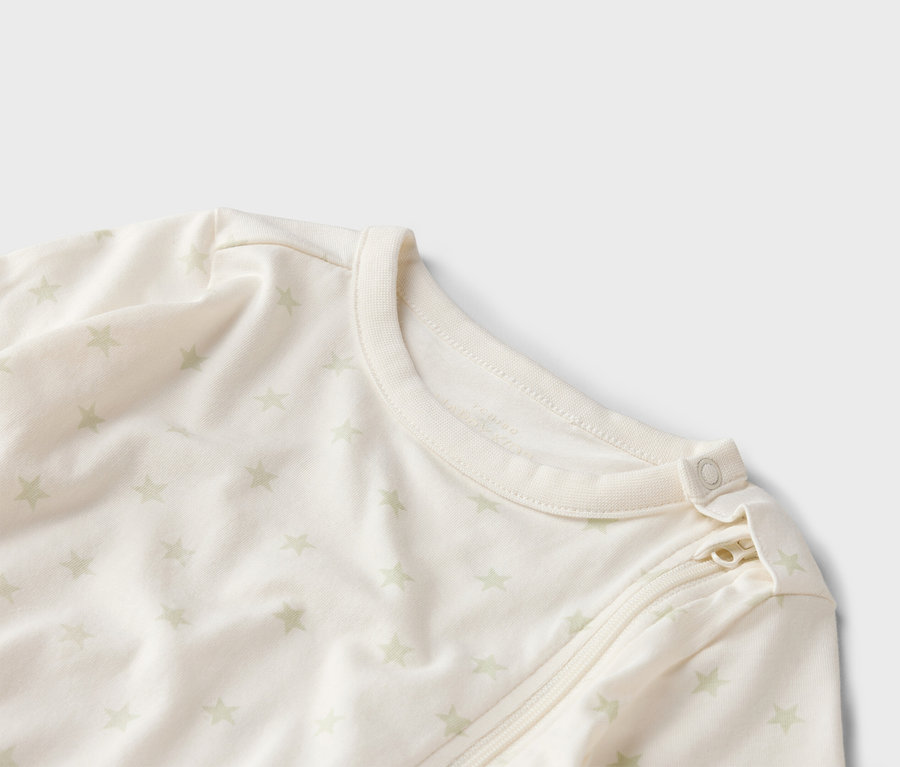 Detailný záber svetlého dojčenského overalu s hviezdicovým vzorom, zipsom a gombíkom pri krku.