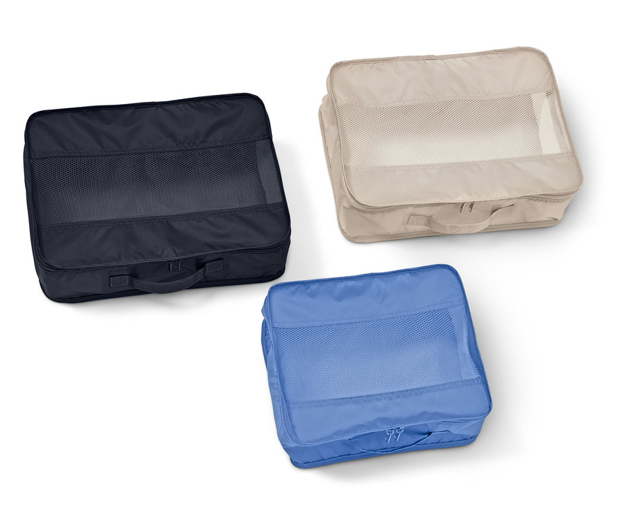 Tri obdĺžnikové organizéry do kufra so sieťovanými okienkami v námorníckej modrej, béžovej a modrej farbe ležia na bielom pozadí.