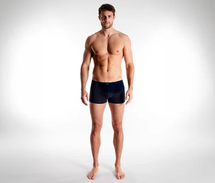 Muž bez trička stojí, má na sebe tmavé boxerky Tom Tailor Colorado.