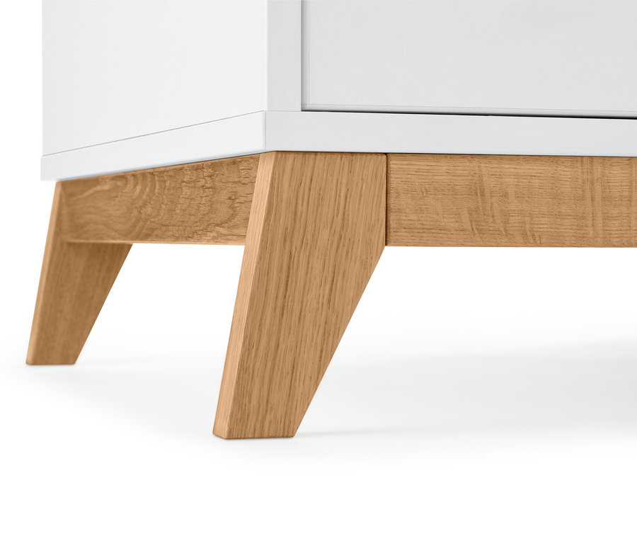 Detail bielej odkladacej skrinky s drevenými nohami.