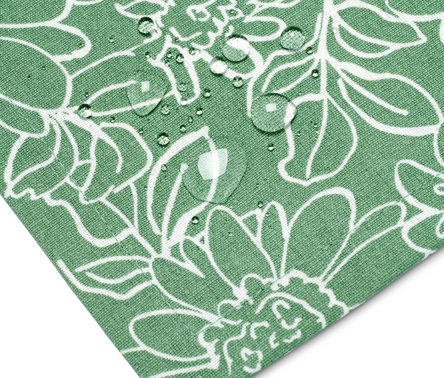 Detail rohu zeleného obrusu na záhradný stôl so vzorom bielych kvetov a kvapkami vody.