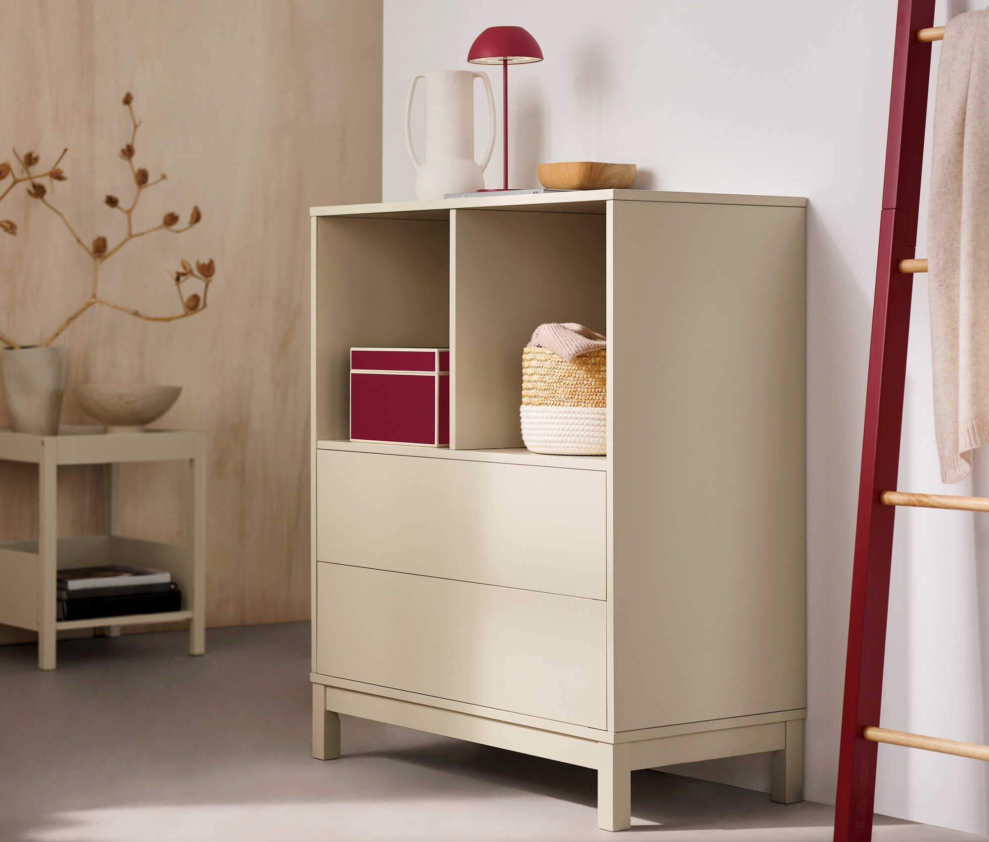 V izbe stojí vysoká komoda s 2 zásuvkami a červená stolová LED lampa s akumulátorom.