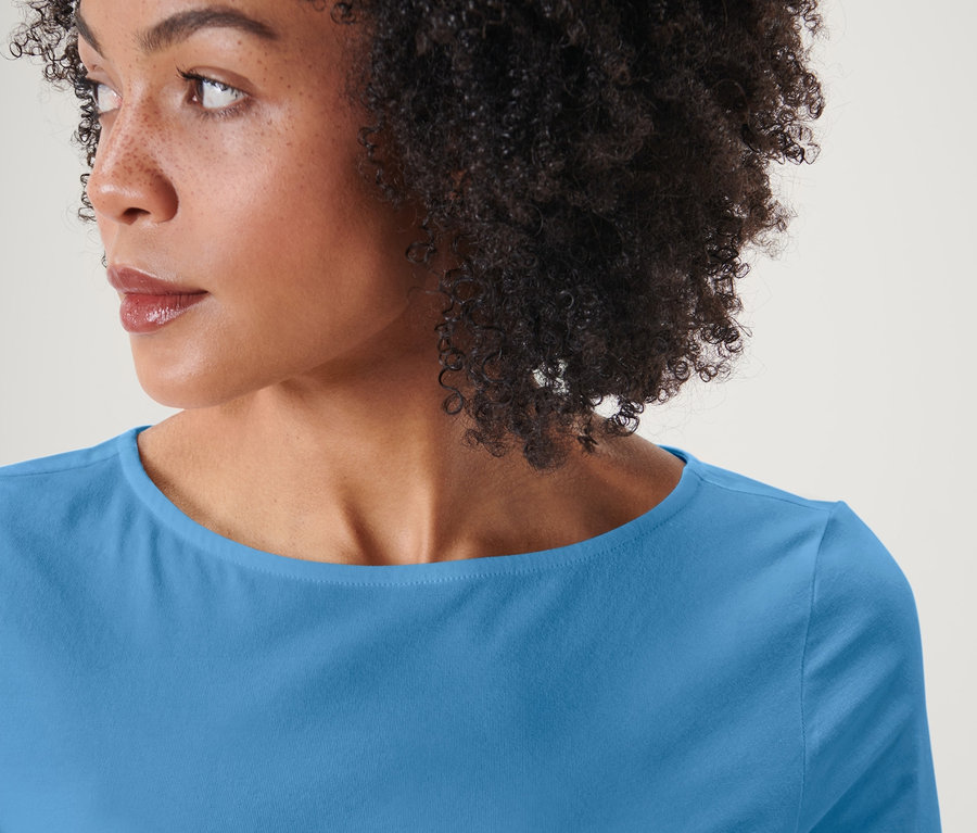 Portrét ženy s afro účesom, oblečenej do svetlomodrého trička s trojštvrťovým rukávom.