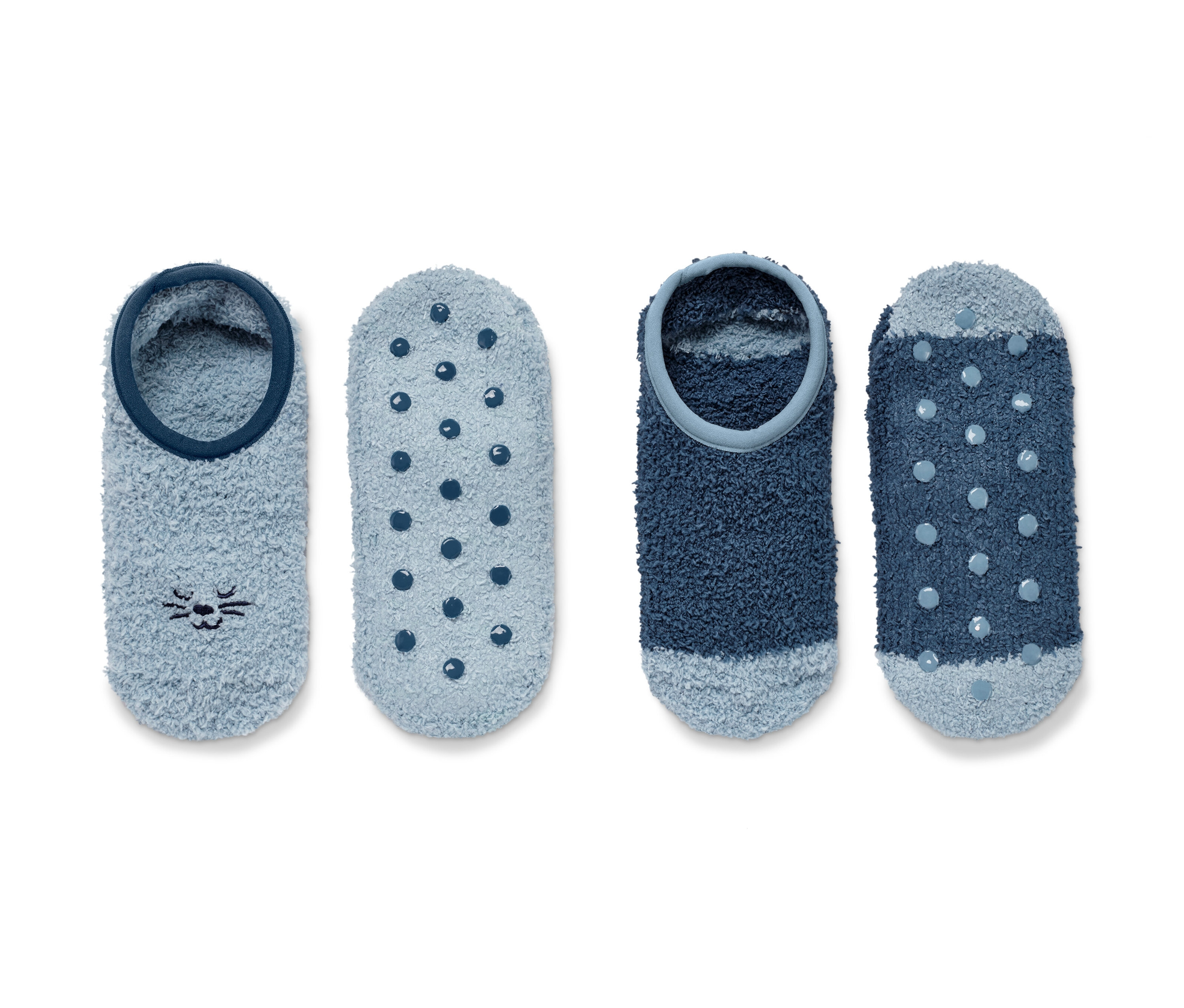 Dva páry ponožkových papúč. Jeden pár je svetlomodrý s motívom mačky, druhý pár je tmavomodrý s bodkami.