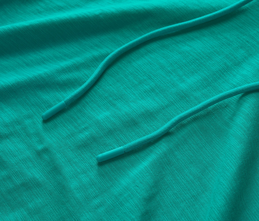 Detailný záber na tyrkysovú džersejovú mikinu s kapucňou so sťahovacou šnúrkou.