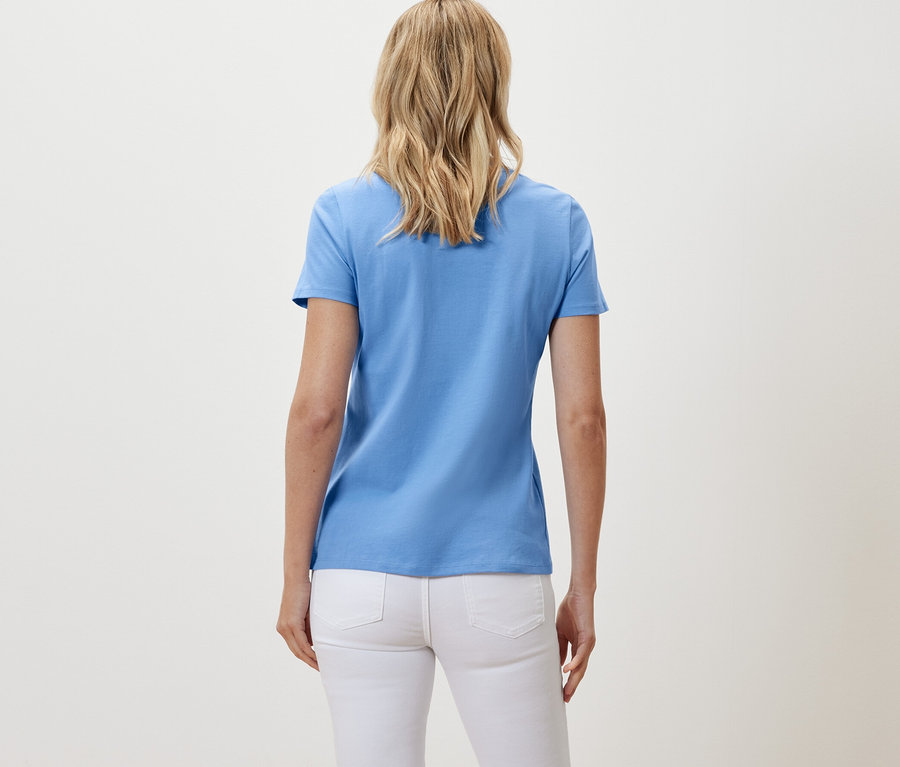 Pohľad zozadu na ženu v bielych džínsoch a svetlomodrom tričku.